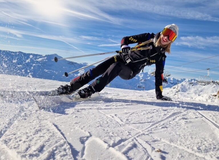 Ski racer in black gear carving across a snowy alpine slope
