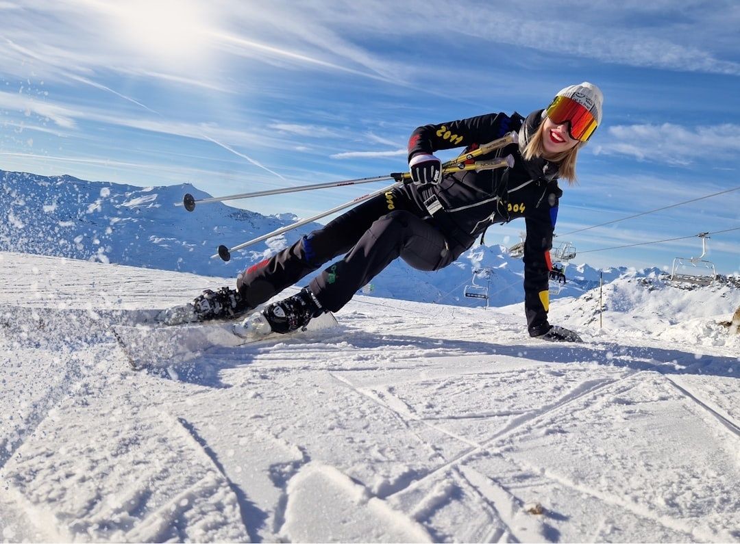 Ski racer in black gear carving across a snowy alpine slope